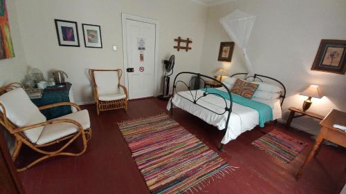 una camera da letto con un letto e sedie e una croce sul muro di Room @ Irissa Sanctuary a De Rust