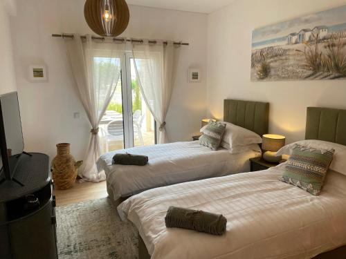 阿爾布費拉的住宿－Villa Cascata, 3 bedroom, Pool, close to Olhos de Agua，一间卧室设有两张床、一台电视和一扇窗户。