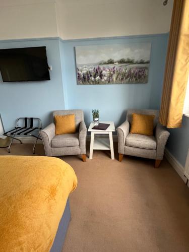 a bedroom with two chairs and a tv on the wall at Between the Bays exclusively for Adults in Llandudno