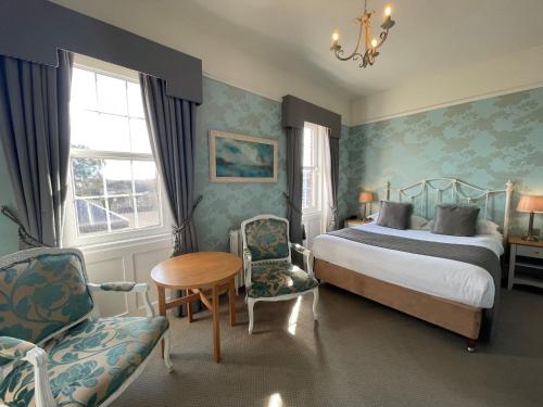 a bedroom with a bed and a table and chairs at Park Farm Hotel in Norwich