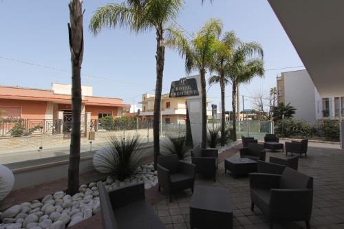 een patio met stoelen en palmbomen in een winkelcentrum bij Hotel Presidente in Porto Cesareo