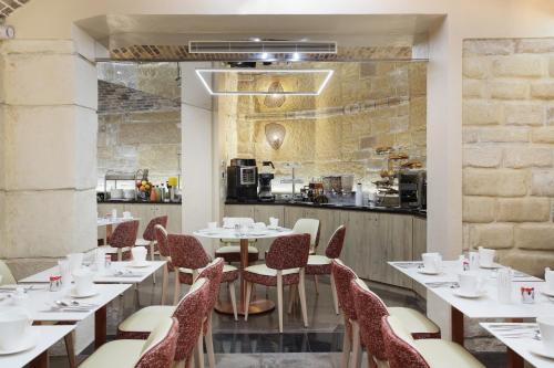 パリにあるグラン ホテル サン ミッシェルのテーブルと椅子のあるレストラン、キッチンが備わります。