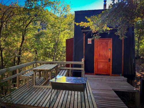 eine Holzterrasse mit einer Bank und einer Holztür in der Unterkunft Andrómeda Lodge in Las Trancas