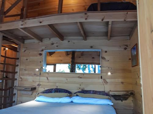 a bed in a log cabin with a window at Puelo Libre in Llanada Grande