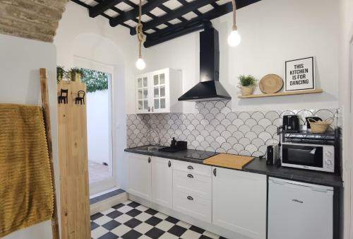 a kitchen with white cabinets and a black counter top at Casa del Sacramento - CASITA CON ENCANTO in Medina Sidonia