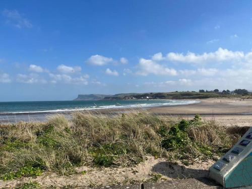 a beach with a bench in the sand and the ocean at Seaside Apartment - 2 storey 2 bedrooms in Ballycastle