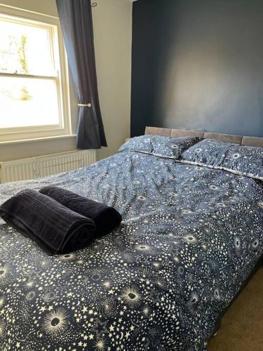 a bedroom with a bed with a blue comforter and a window at Seaside Apartment - 2 storey 2 bedrooms in Ballycastle