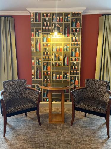 two chairs and a table in a room with a shelf ofiques at Park Farm Hotel in Norwich