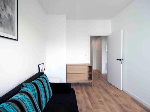 a living room with a black couch and a white wall at Warsaw-Aparts Sonaty in Warsaw