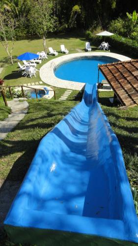 a blue water slide in front of a swimming pool at Pousada Chácara do Rio in Lumiar