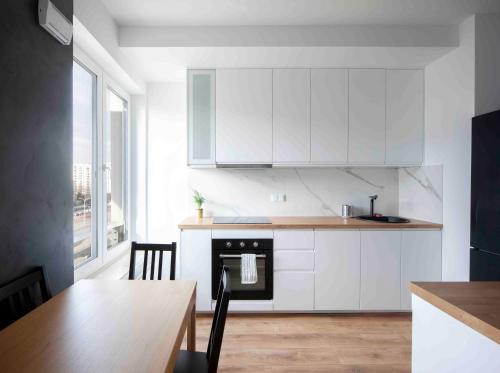 a kitchen with white cabinets and a table and a dining room at Warsaw-Aparts Sonaty in Warsaw