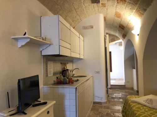 a kitchen with white cabinets and a tv in a room at La Torretta del Senatore in Polignano a Mare