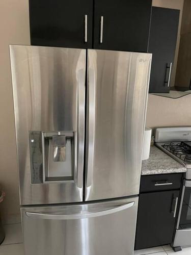 a stainless steel refrigerator in a kitchen with black cabinets at Otay Studio great patio near Otay Crossing & Airport in Tijuana