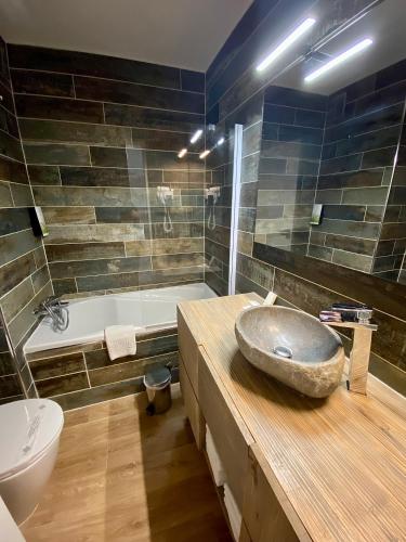 La salle de bains est pourvue d'un lavabo en pierre et d'une baignoire. dans l'établissement Hotel Les Grenadines, au Cap d'Agde