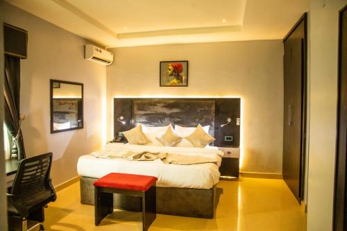 Un dormitorio con una cama grande y un taburete rojo en Zucchini Hotel and apartments, en Umueme
