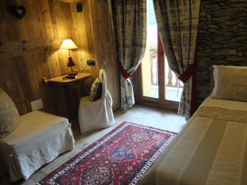 a bedroom with a bed and a chair and a window at La Luge D'Antan Maison d'Hôtes & SPA in Brusson