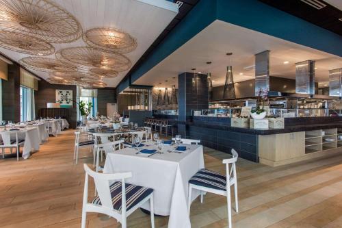 a restaurant with white tables and chairs and a bar at Wyndham Grand Clearwater Beach in Clearwater Beach