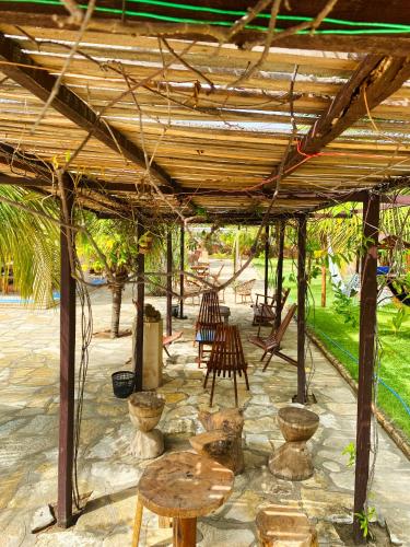 a wooden pergola with chairs and tables under it at Pousada Carmela in Icapuí