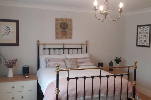 a bedroom with a bed and a chandelier at Pinewood Cotage - Country Walks and Relaxation in Blairgowrie
