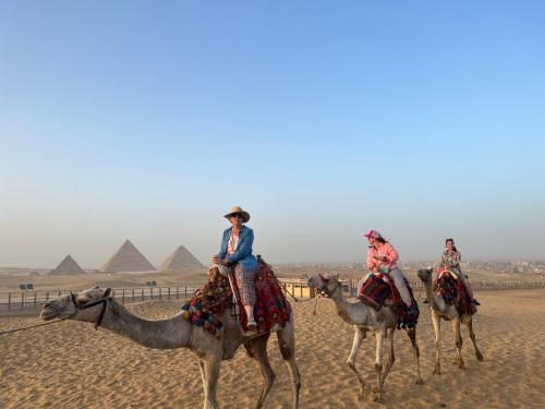four people riding on camels in front of the pyramids at Pyramids top success result in Cairo