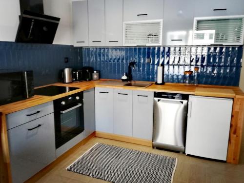 a kitchen with white appliances and blue tiles at Apartament Sand&Blue in Sztutowo