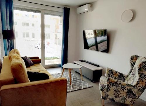 uma sala de estar com um sofá e cadeiras e uma janela em Apartament Sand&Blue em Sztutowo