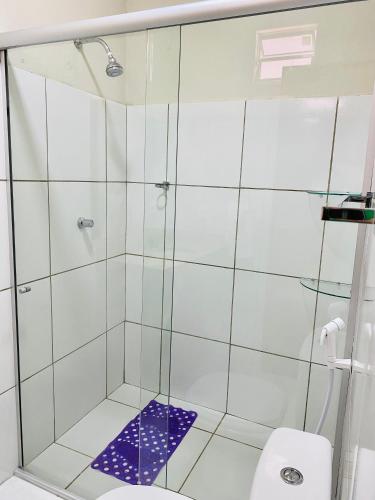 a shower with a glass door next to a toilet at Pousada Carmela in Icapuí