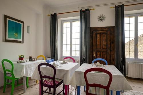 une salle à manger avec deux tables et des chaises colorées dans l'établissement La Chaumière, Demeure d'hôtes, à Lauris