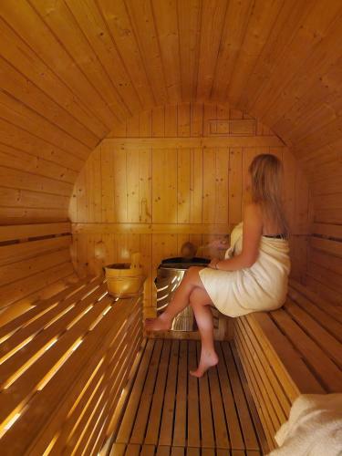 a woman is sitting in a sauna at Kaszubskie Wzgórze - Całoroczne Domki Drewniane in Perlino