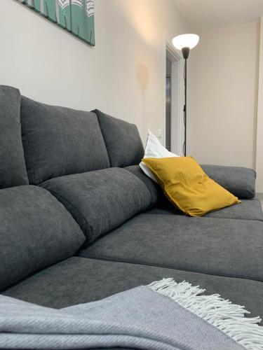 a gray couch with a yellow pillow on it at Casa Pablo II Aptº Tranquilo, a cinco minutos del Puerto de la Cruz in Los Realejos