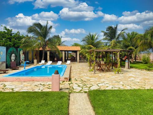 a swimming pool with chairs and a gazebo at Pousada Carmela in Icapuí