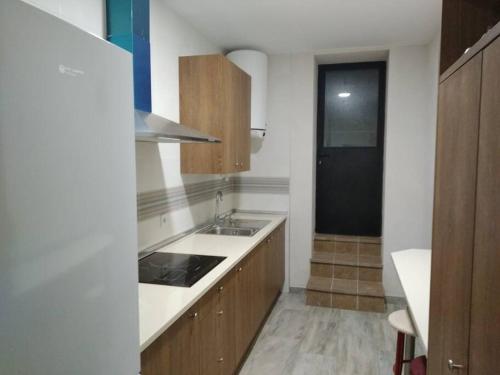 a kitchen with wooden cabinets and a sink and a black door at Casita Colibrí in La Puebla de Montalbán