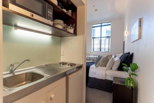 Una cocina con fregadero y una cama en una habitación. en Bright CBD Studio -Near SkyTower - WiFi - Cityscape, en Auckland