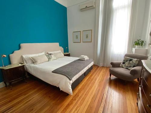 a bedroom with blue walls and a bed and a chair at Hotel Chemin in Buenos Aires