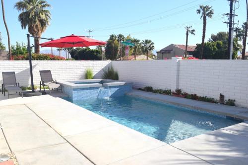 a swimming pool with two chairs and an umbrella at West Racquet Club Art Room in Palm Springs