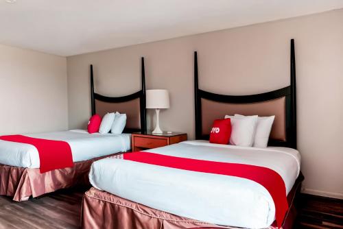 duas camas num quarto de hotel com lençóis vermelhos e brancos em OYO Hotel Alice TX Hwy 281 West em Alice