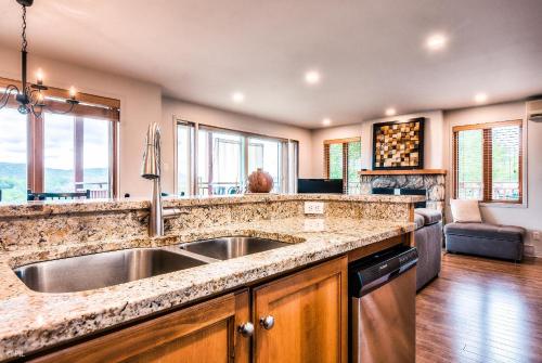 a kitchen with a sink and a living room at Hauts-bois Ski Inout 2brs Wpool Access 193-1 in Mont-Tremblant