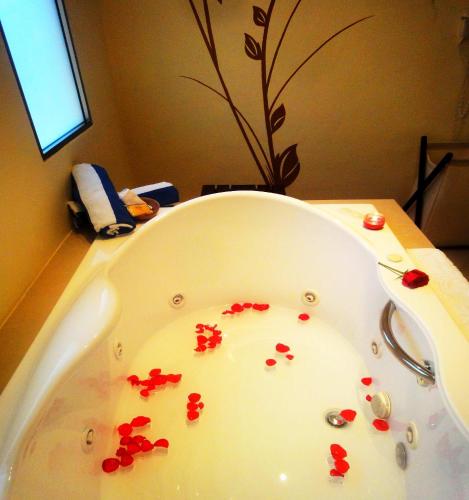 a bathroom with a tub with red flowers in it at Merida Santiago Hotel Boutique in Mérida
