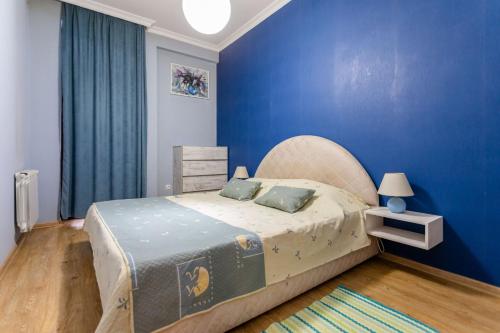 a bedroom with a large bed with a blue wall at Apartment 16 in Tbilisi City