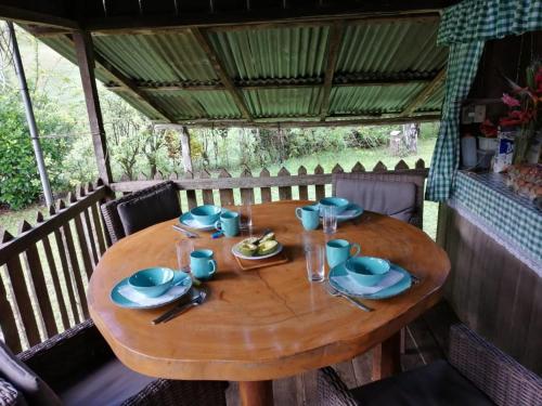 una mesa de madera con platos y vasos. en Finca Sueno de Osa, en Puerto Jiménez