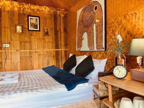 1 dormitorio con 1 cama y reloj sobre una mesa en 3 Pok Maewang jinxiang Gold elephant park, en Ban Mae Sapok Noi