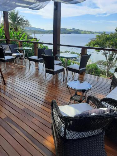a deck with tables and chairs and a view of the water at Solarium de Escarpas Suítes in Capitólio
