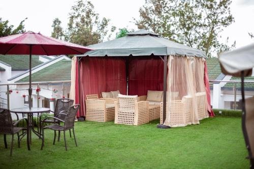 a garden with a gazebo with chairs and a table at Ndaru Luxury Suites in Kigali