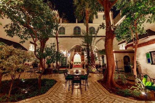 un patio con mesa, sillas y árboles en Riad Catalina en Marrakech