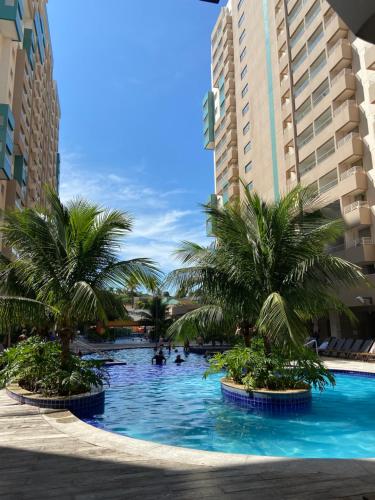 een zwembad met palmbomen in het midden van gebouwen bij Olímpia Park Resort Apto in Olímpia