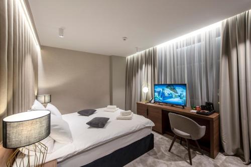 a bedroom with a bed and a desk and a television at Hotel Turist in Varaždin