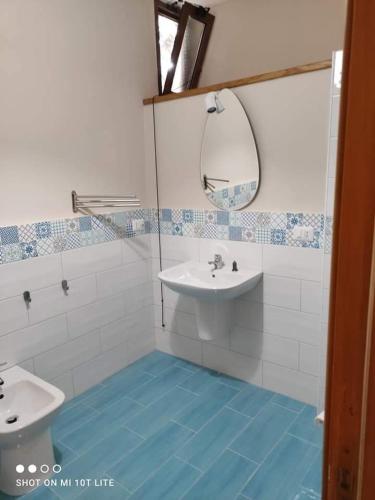 a bathroom with a sink and a mirror and blue floor at Ristorante Paisà. Cibo e Ospitalità in Agnone