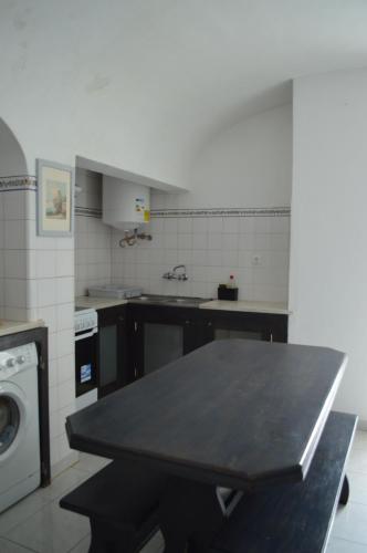 a kitchen with a table and a washing machine at Évora Romana Alojamentos T1 Templo Diana in Évora