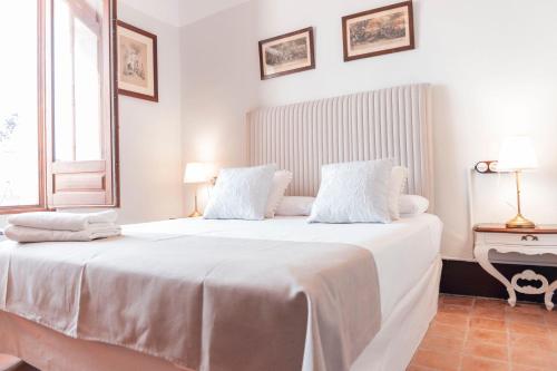 a white bedroom with a large bed with white sheets at Castell Granadella in L'Ampolla