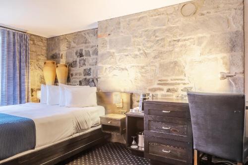 a bedroom with a bed and a stone wall at Hotel Maison du Général in Quebec City